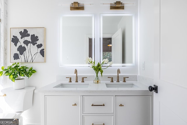 full bath with double vanity, a sink, and toilet