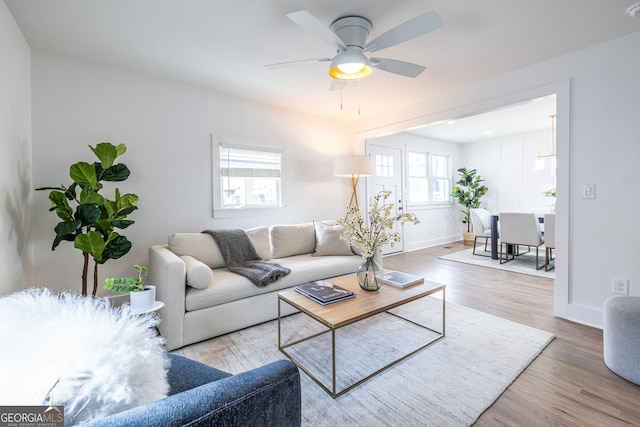 living area featuring ceiling fan, baseboards, and wood finished floors