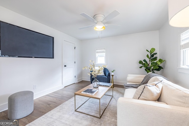 living area with a ceiling fan, baseboards, and wood finished floors