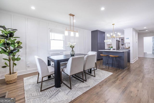 dining space featuring recessed lighting, an inviting chandelier, dark wood finished floors, and a decorative wall