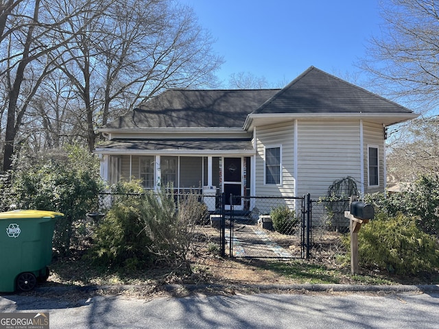 view of front of home with a fenced front yard, a gate, and a shingled roof