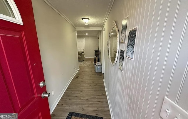 hall with ornamental molding, a textured ceiling, baseboards, and wood finished floors