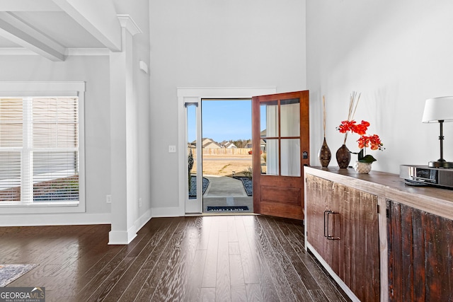 entryway with dark wood-style floors, beam ceiling, a high ceiling, and baseboards