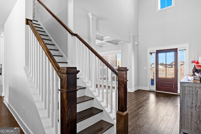 foyer entrance featuring dark wood-style floors, a wealth of natural light, ornate columns, and baseboards