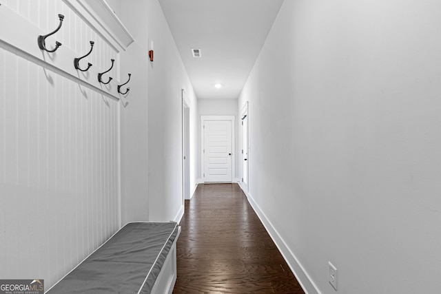 hall featuring dark wood-type flooring, visible vents, and baseboards