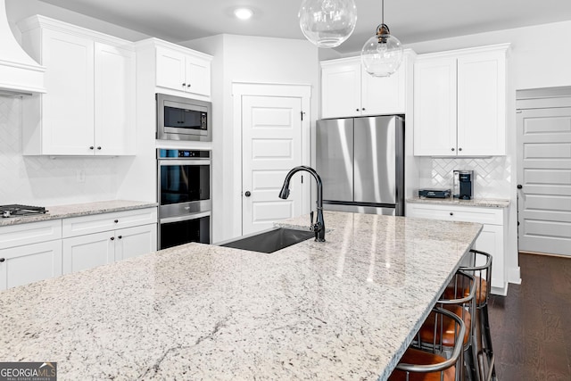 kitchen featuring dark wood-style floors, custom exhaust hood, appliances with stainless steel finishes, white cabinets, and a sink