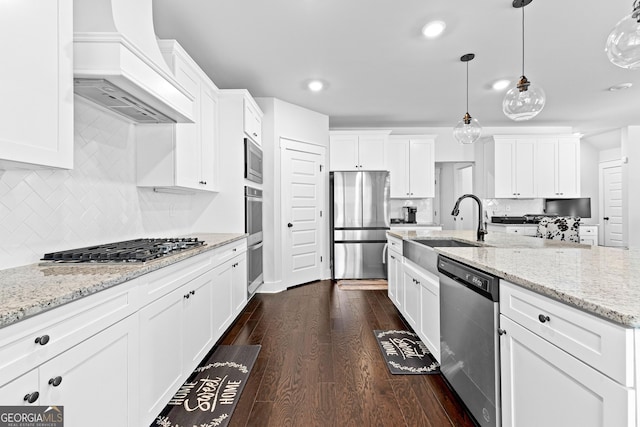 kitchen featuring dark wood-style floors, hanging light fixtures, appliances with stainless steel finishes, white cabinets, and premium range hood