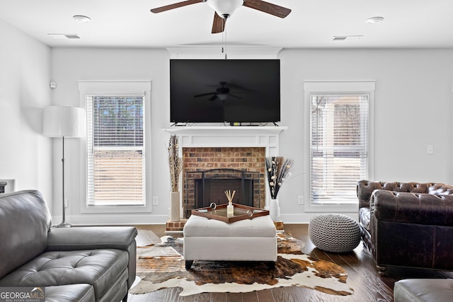 living room featuring a fireplace, plenty of natural light, wood finished floors, and visible vents