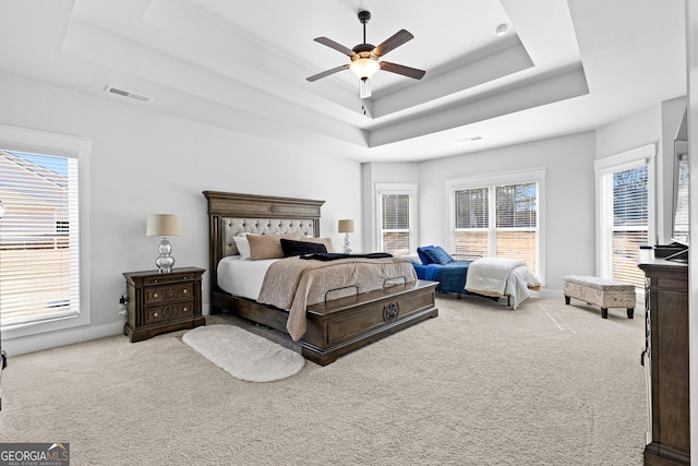 bedroom featuring a ceiling fan, a tray ceiling, visible vents, and carpet