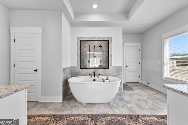 full bath featuring visible vents, walk in shower, vanity, a freestanding tub, and tile walls