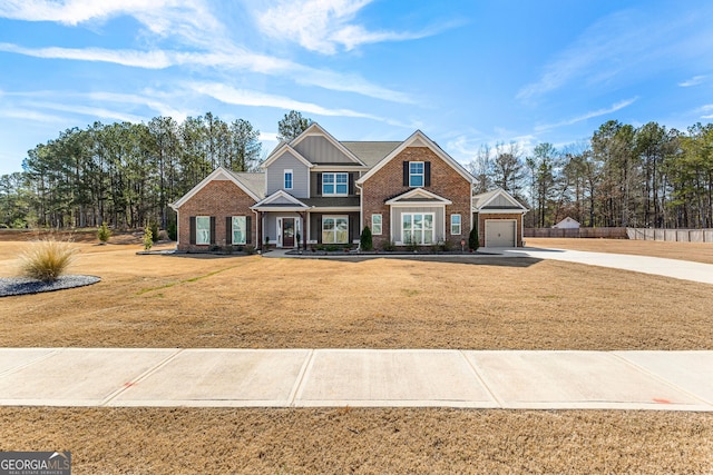 craftsman inspired home featuring concrete driveway, a front lawn, an attached garage, and brick siding