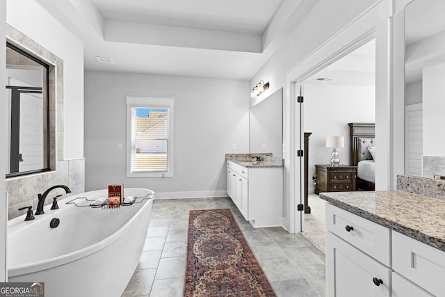 ensuite bathroom featuring ensuite bathroom, a freestanding tub, visible vents, vanity, and a tray ceiling