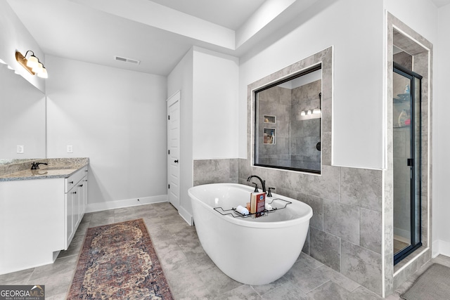 bathroom with a soaking tub, visible vents, a tile shower, and vanity