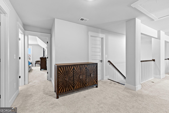 hall featuring attic access, visible vents, carpet flooring, and an upstairs landing