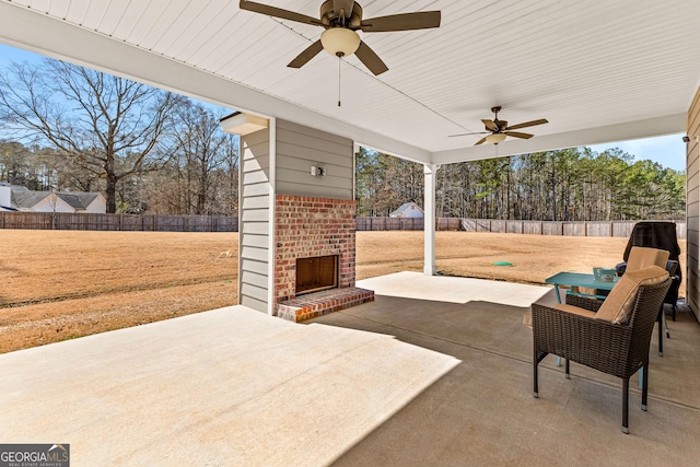 view of patio / terrace with an outdoor brick fireplace, a fenced backyard, and ceiling fan