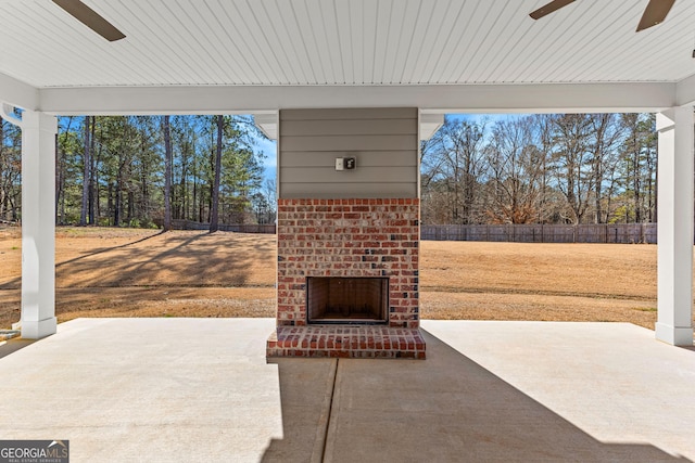 view of patio / terrace with an outdoor brick fireplace, fence, and a ceiling fan