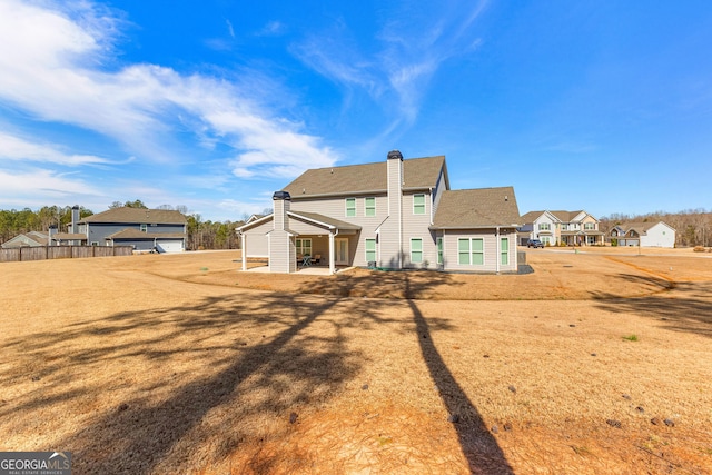 back of property featuring a yard, a residential view, fence, and a patio