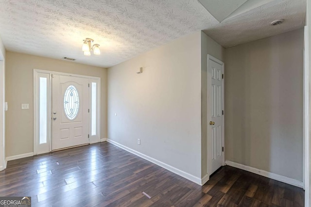 entrance foyer with dark wood-style flooring, visible vents, a textured ceiling, and baseboards