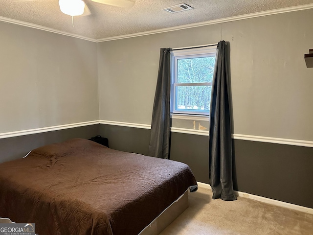 carpeted bedroom featuring visible vents, ornamental molding, ceiling fan, a textured ceiling, and baseboards