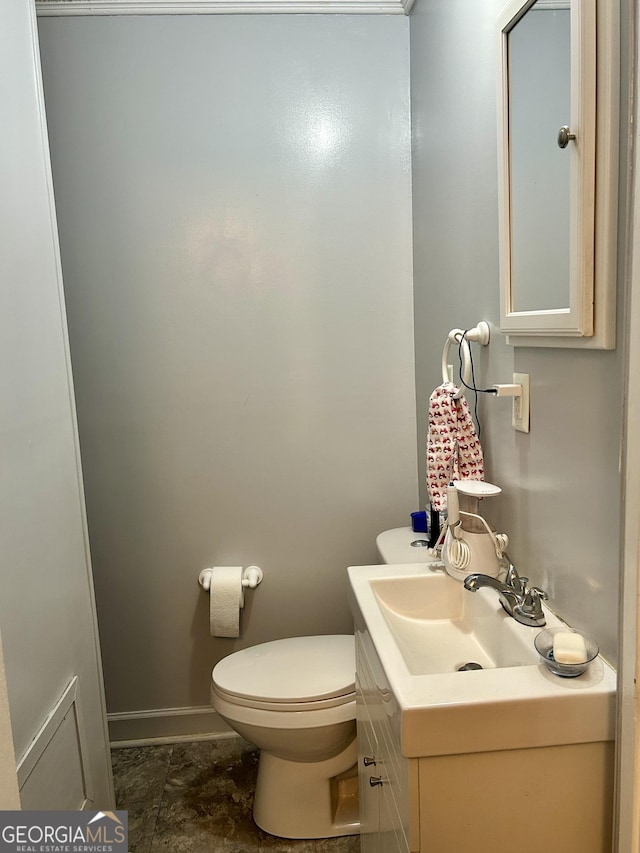 half bath featuring vanity, toilet, and baseboards