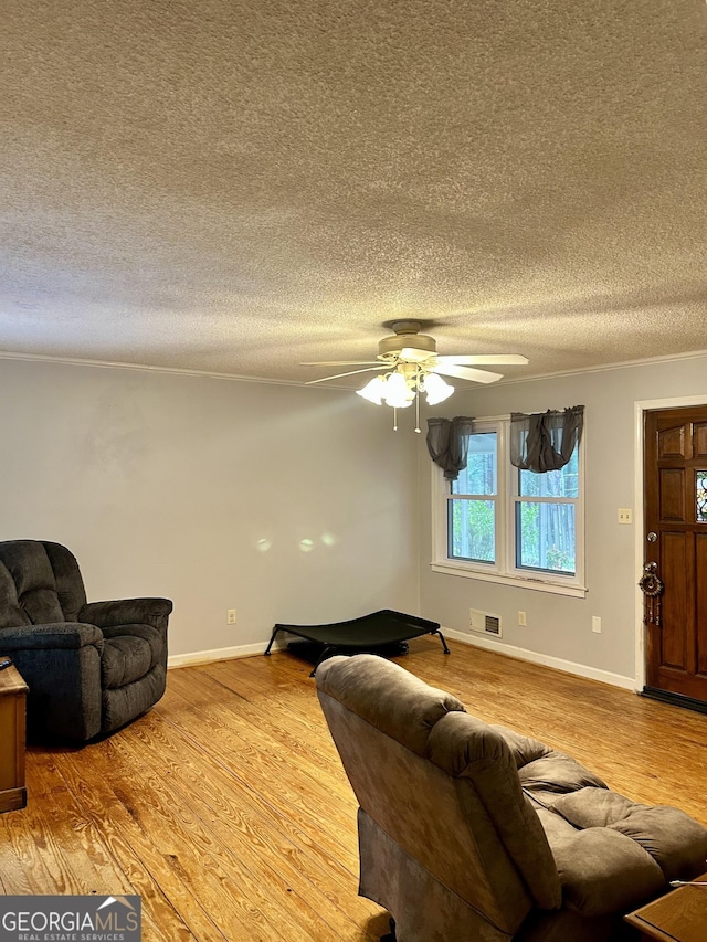 living room with baseboards, visible vents, a textured ceiling, and light wood finished floors