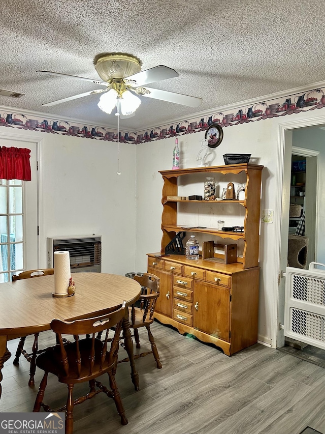 dining room featuring light wood-style floors, crown molding, ceiling fan, and a textured ceiling