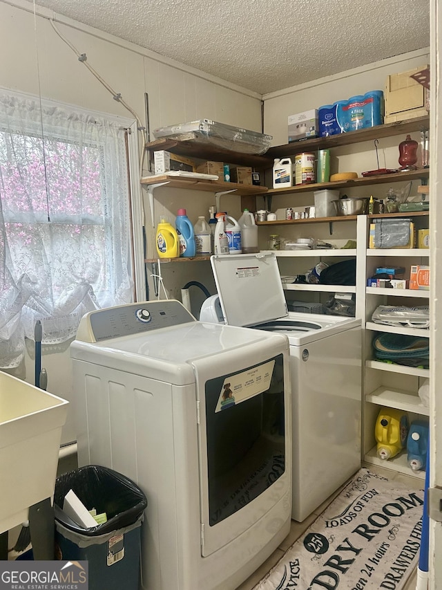 washroom featuring a textured ceiling, laundry area, independent washer and dryer, and a sink