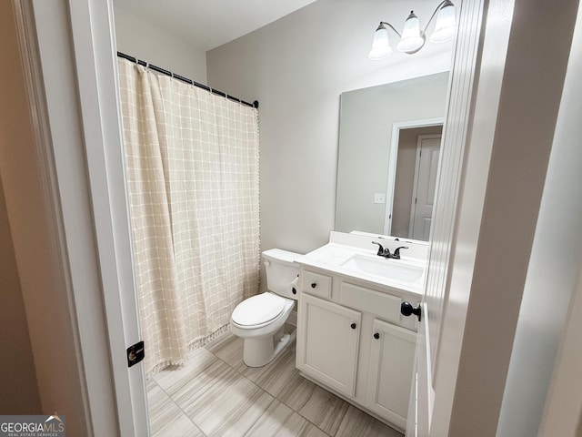 full bath with curtained shower, vanity, and toilet