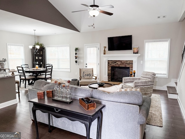 living area featuring visible vents, dark wood-style floors, vaulted ceiling, a fireplace, and ceiling fan with notable chandelier