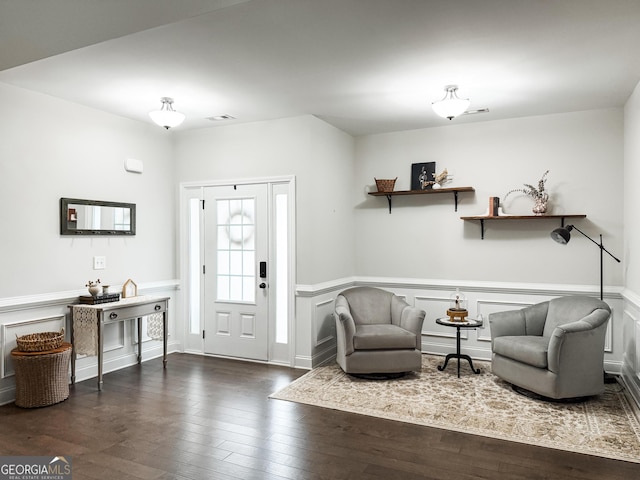 foyer entrance featuring a wainscoted wall, visible vents, dark wood finished floors, and a decorative wall