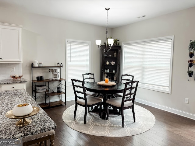 dining space featuring a wealth of natural light, visible vents, dark wood finished floors, and a notable chandelier