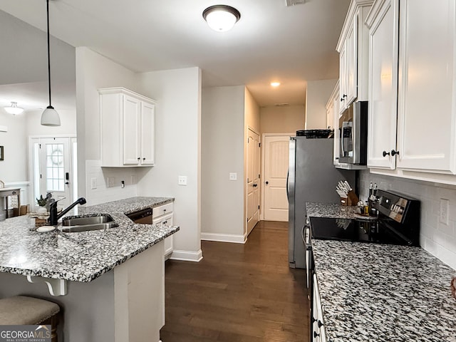 kitchen featuring stone countertops, white cabinets, dark wood finished floors, appliances with stainless steel finishes, and a sink