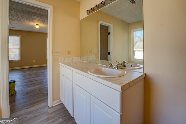 bathroom featuring a textured ceiling, wood finished floors, a wealth of natural light, and baseboards