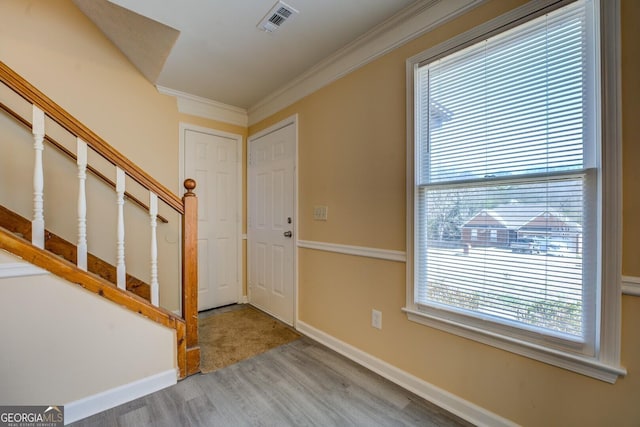 entrance foyer with crown molding, visible vents, wood finished floors, baseboards, and stairs