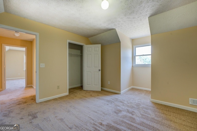 unfurnished bedroom featuring a closet, carpet flooring, a textured ceiling, and baseboards