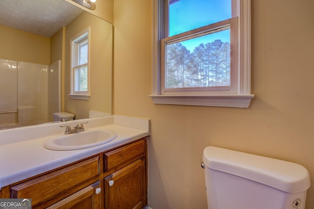 full bathroom with toilet, walk in shower, a textured ceiling, and vanity