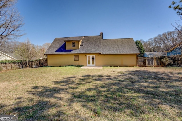 back of property with french doors, a fenced backyard, a lawn, and a chimney