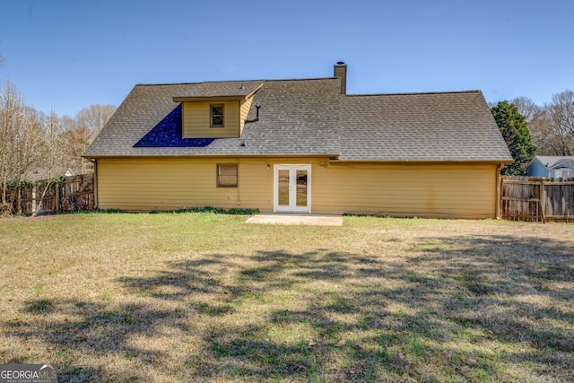 back of house with roof with shingles, fence, a lawn, and french doors