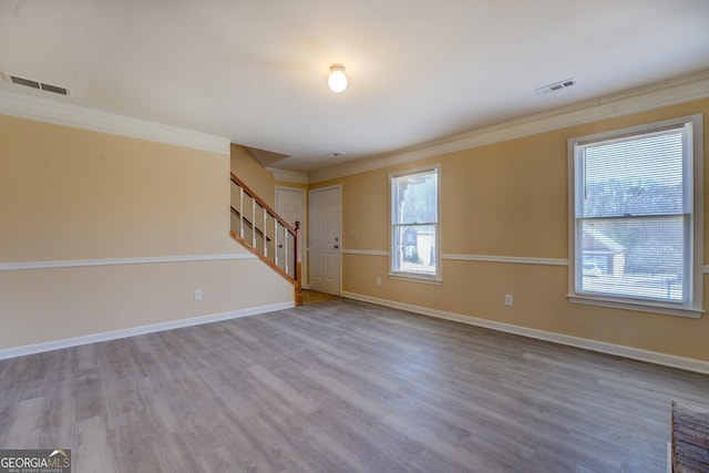 spare room featuring stairway, wood finished floors, visible vents, and crown molding