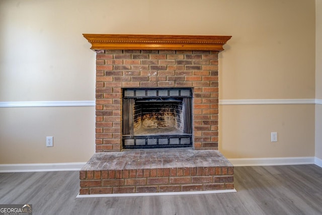 room details with a brick fireplace, baseboards, and wood finished floors