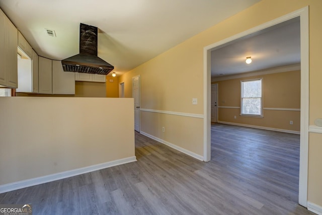 spare room with ornamental molding, wood finished floors, visible vents, and baseboards