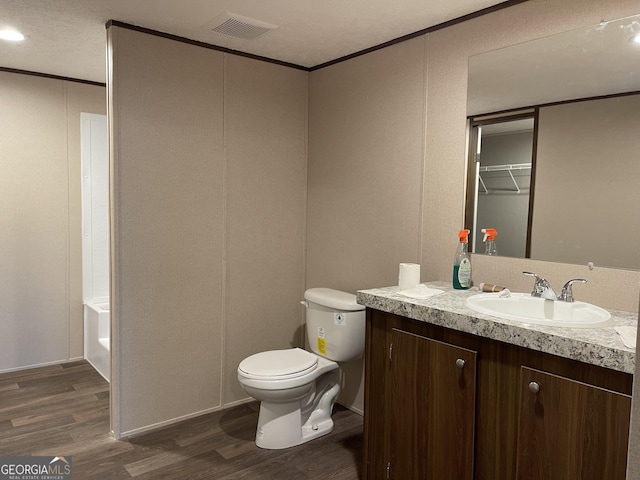 full bath featuring toilet, wood finished floors, vanity, visible vents, and ornamental molding