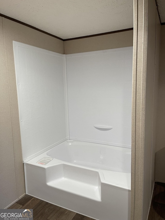 bathroom featuring a textured ceiling, a tub to relax in, and wood finished floors