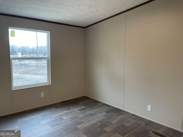 spare room featuring visible vents, a textured ceiling, ornamental molding, and wood finished floors