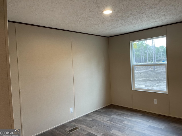 spare room with a textured ceiling, visible vents, and wood finished floors