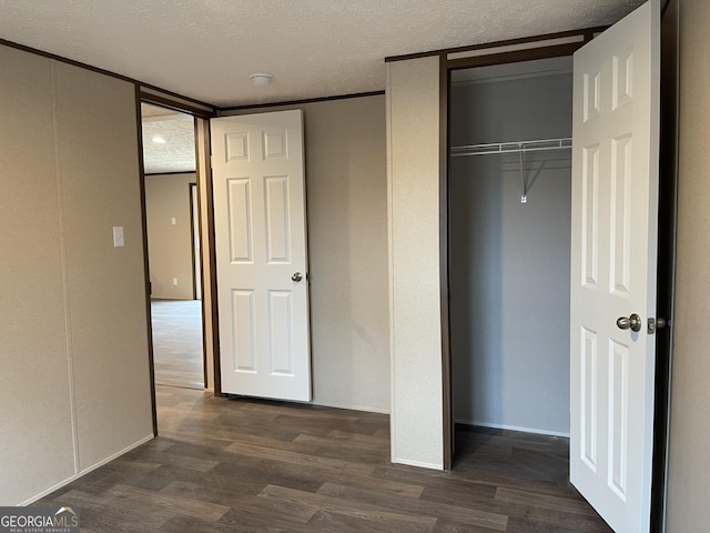 unfurnished bedroom with dark wood-type flooring, a closet, and a textured ceiling