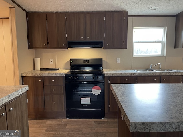 kitchen featuring black gas range oven, dark wood-style floors, extractor fan, a textured ceiling, and a sink