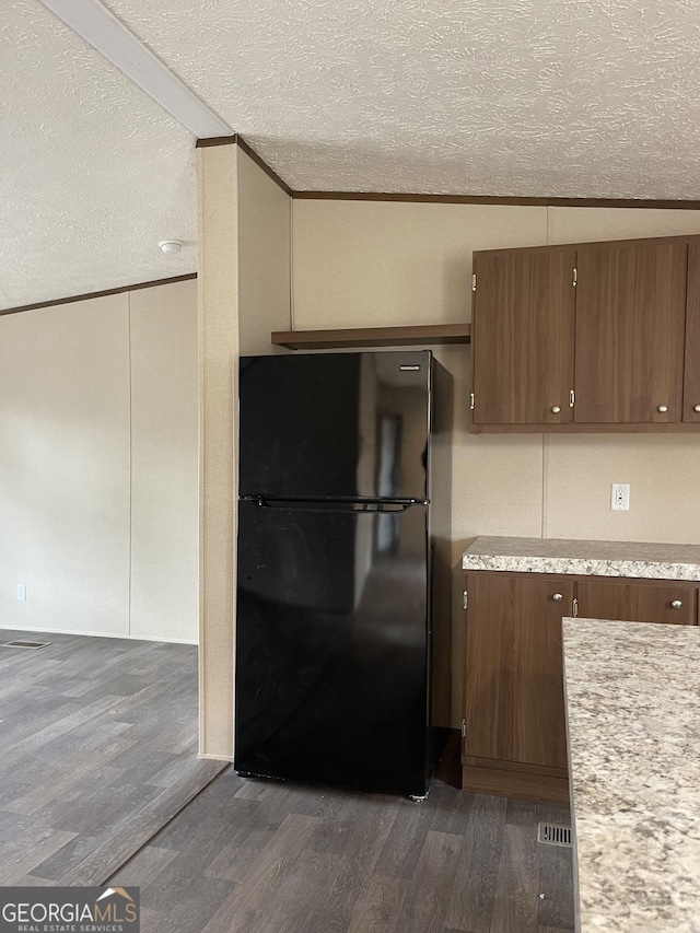 kitchen featuring dark wood-style floors, light countertops, a textured ceiling, and freestanding refrigerator