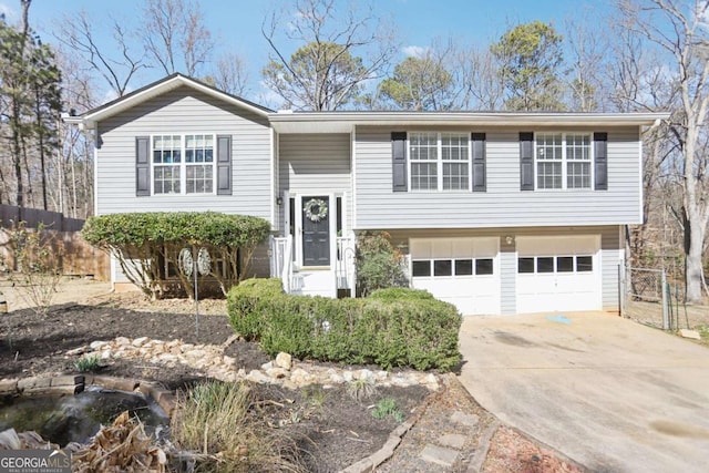 split foyer home with driveway, an attached garage, and fence