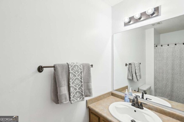 bathroom featuring toilet, visible vents, a shower with shower curtain, and vanity